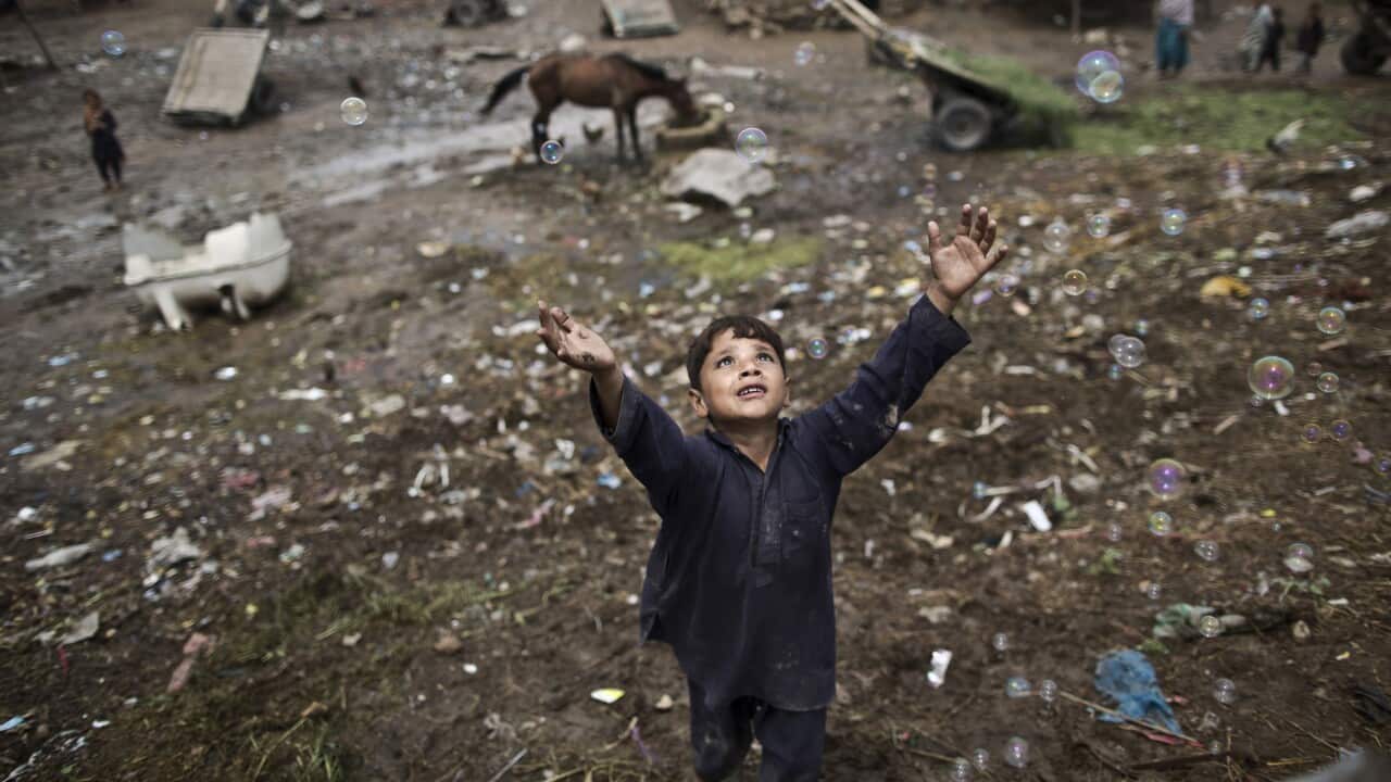 Zawar Khan, an Afghan refugee child chases bubbles released by other children while playing on the outskirts of Islamabad, Pakistan. Photo by Muhammed Muheisen. 