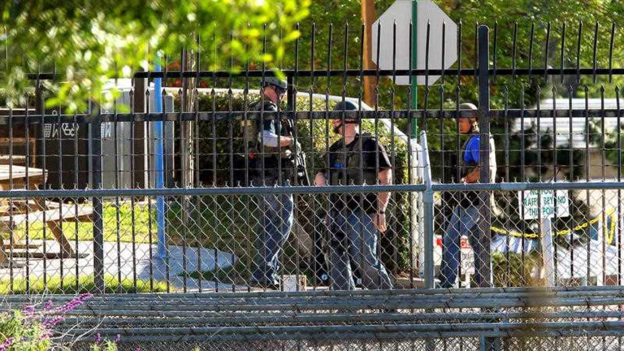 Law enforcement personnel wait by the parking garage in front of building 26 as they respond to reports of gunshots
