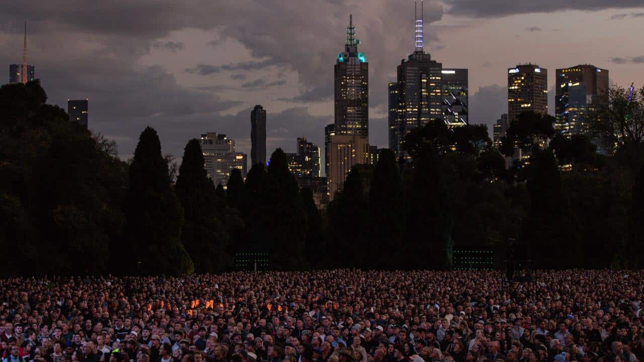 A huge crowd of people with a city skyline in the background.