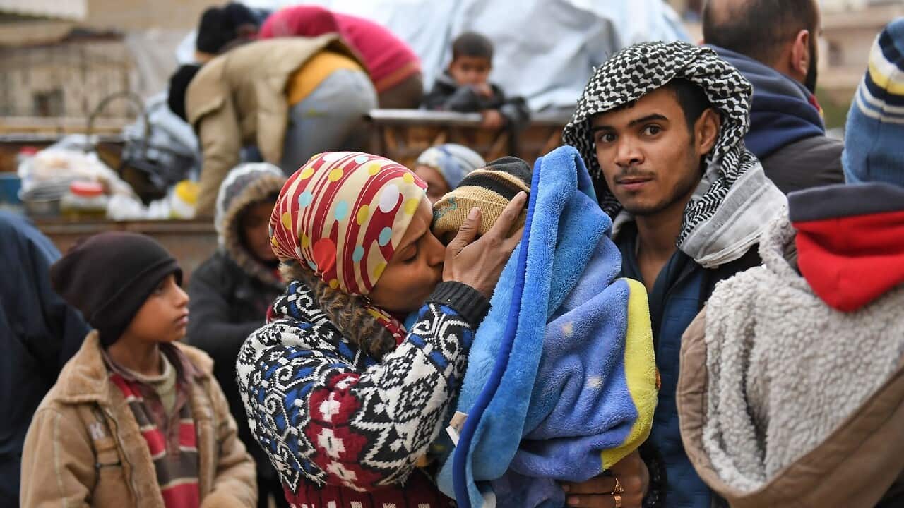 A Syrian woman kisses her infant as she arrives with others who fled from the town of Jandairis in the southwestern corner of the Afrin enclave.