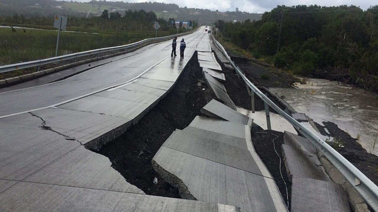 People walk along a road damaged by an earthquake in southern Chile