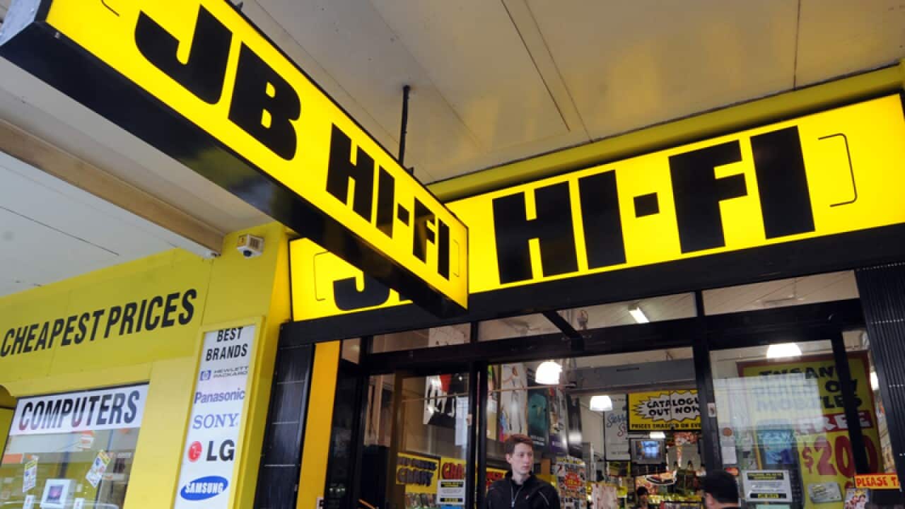 Pedestrains walk past a JB HI-FI store in Melbourne