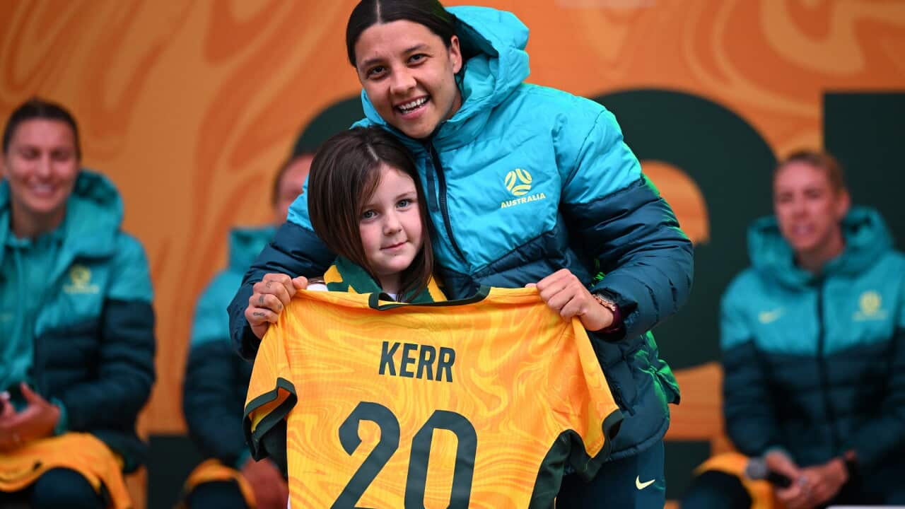 Sam Kerr (right) holds a jersey with her name and number 20 on it as she hugs a young female fan at Federation Square in Melbourne on 11 July 2023.