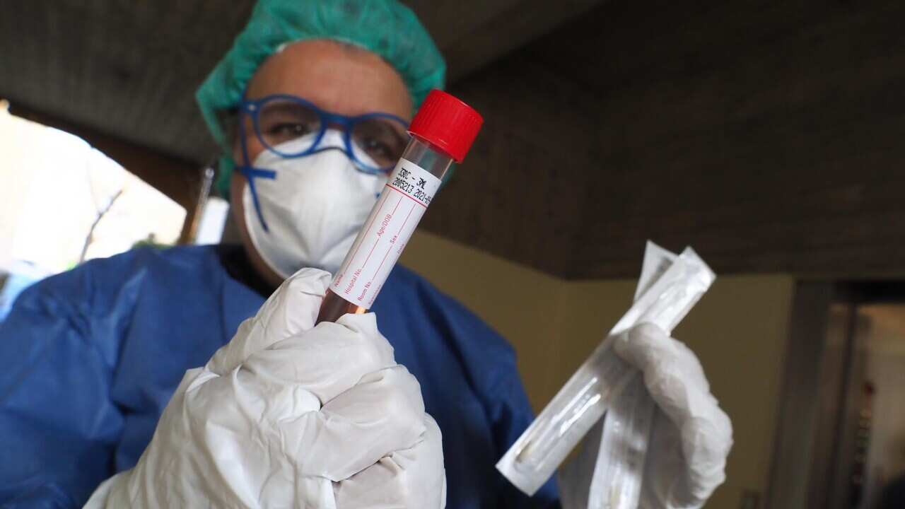 A health worker wearing overalls and protective masks perform a swab test.