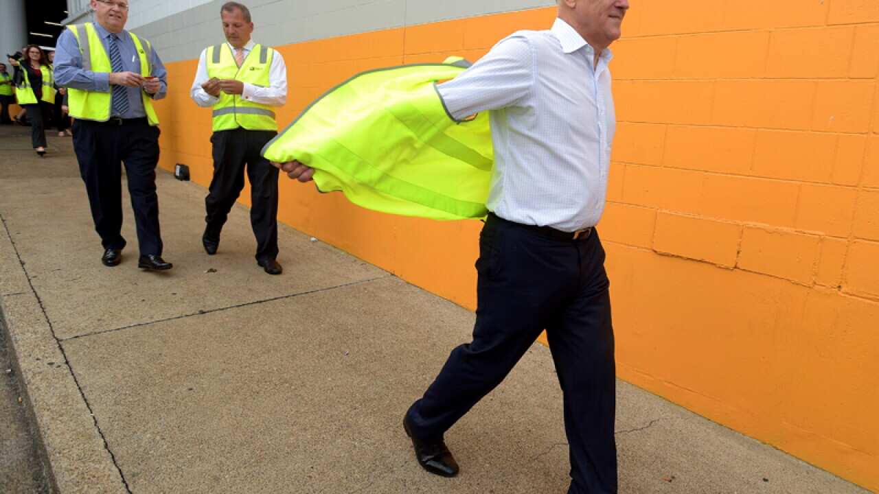 Malcolm Turnbull takes off a high visibility vest