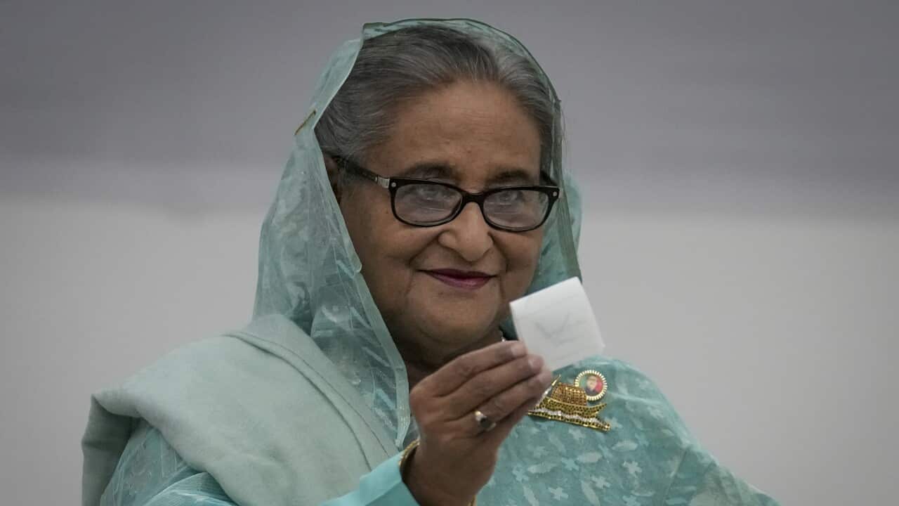 A woman shows her ballot paper after casting her vote.
