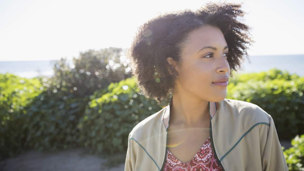 Pensive young woman looking away at sunny beach