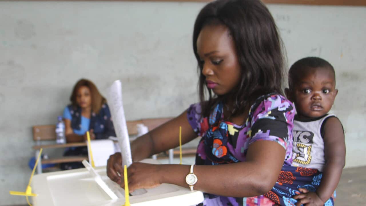 A woman drop her vote into a ballot box in Maputo, Mozambique.