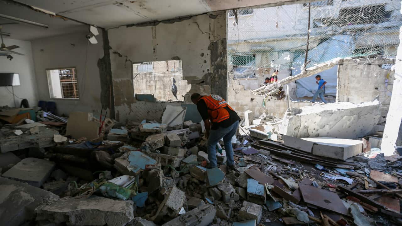 A man inspecting rubble inside a damaged building.