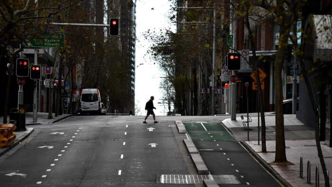 مردی در حال عبور از یکی از چهارراههای مرکز شهر سیدنی.