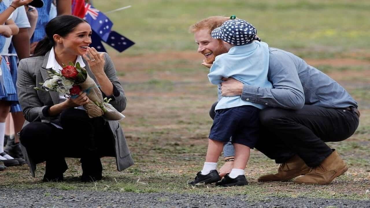 Meghan smiles five-year-old Luke Vincent hugs Prince Harry.