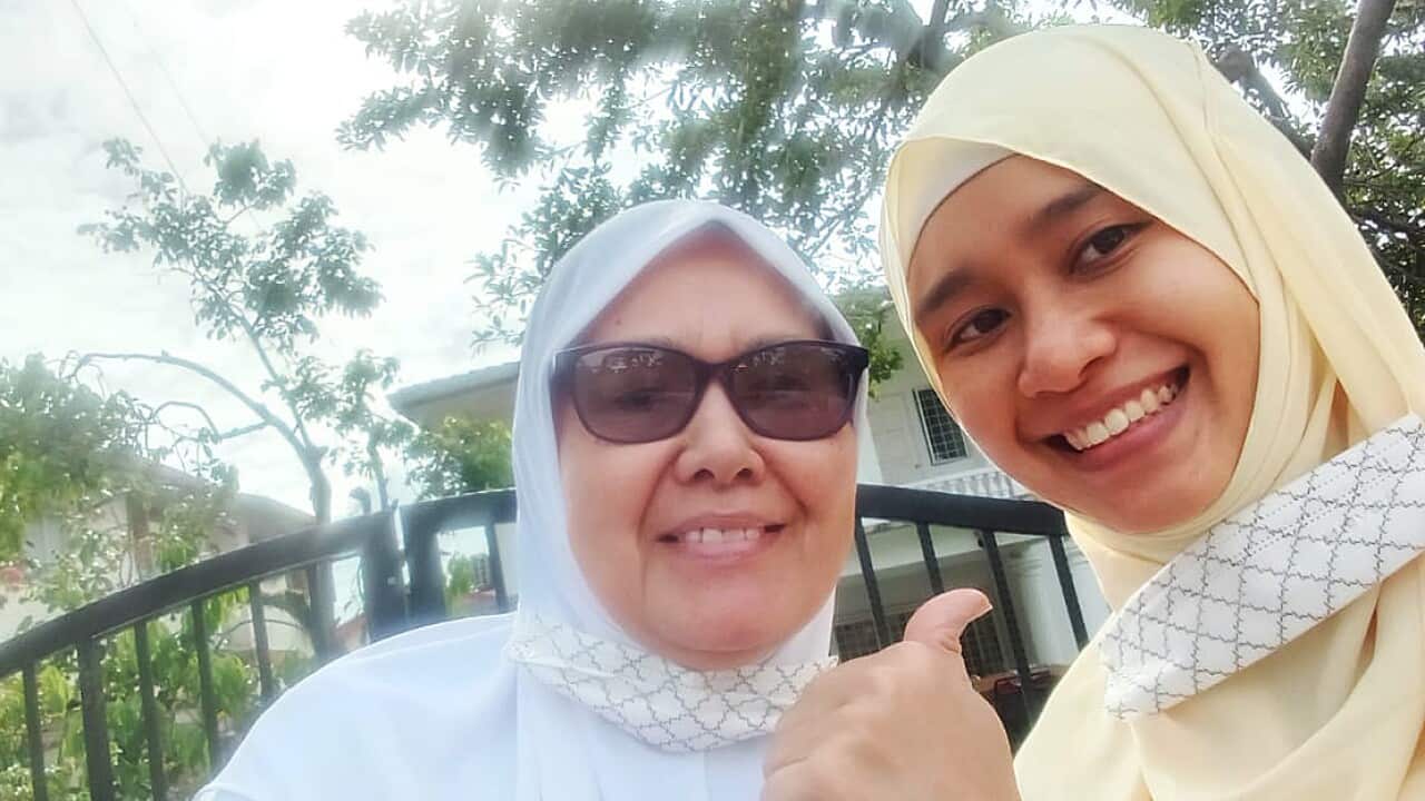 Two women in headscarves smiling at the camera.