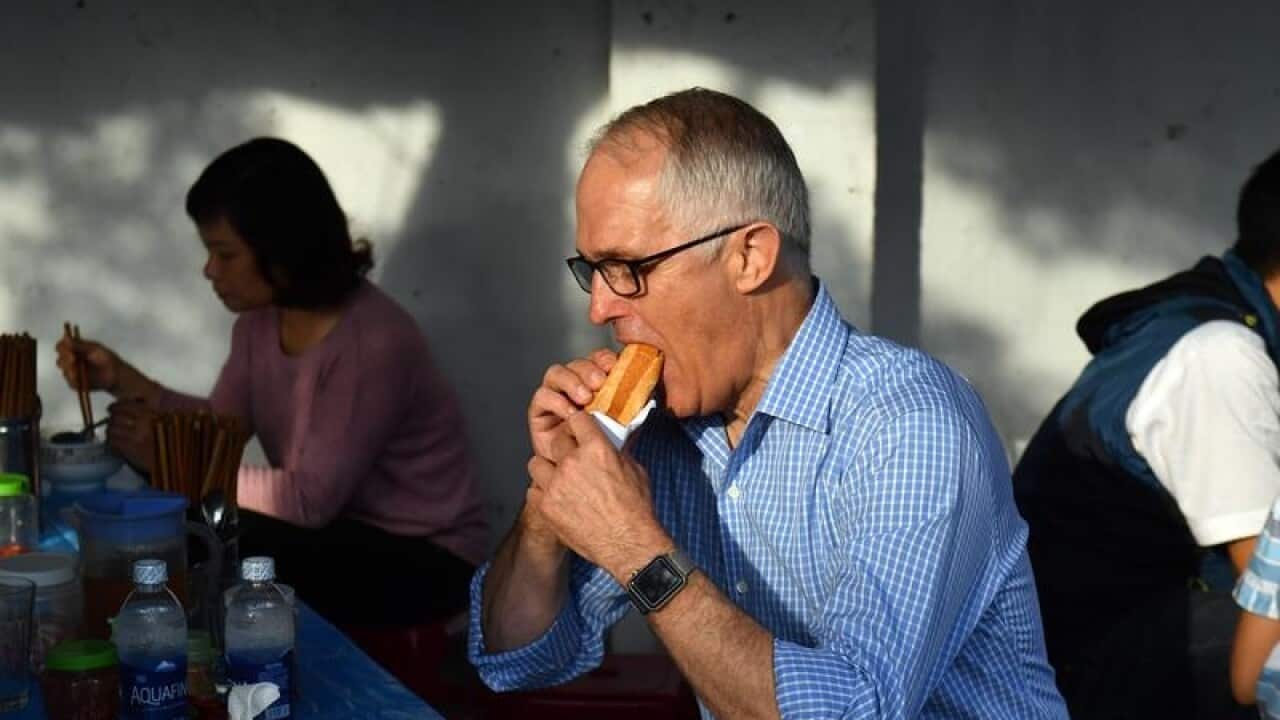 Australia's Prime Minister Malcolm Turnbull eats a vietnamese roll