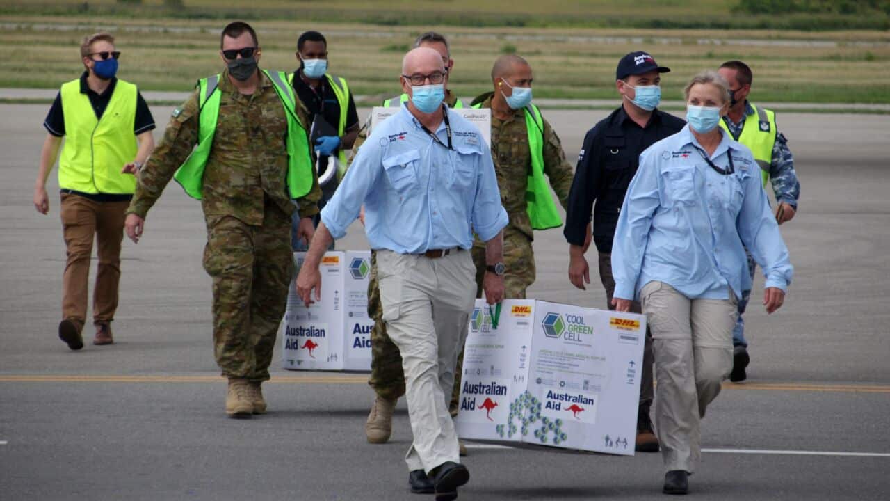 Australian officials carry boxes containing some 8,000 initial doses of the AstraZeneca vaccine following their arrival at Port Moresby on 23 March.