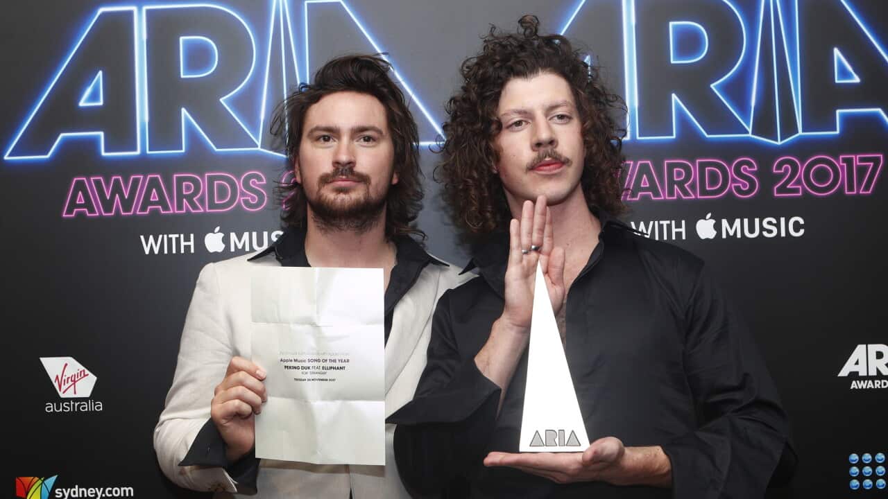 Two young men hold up a white and pointed award.