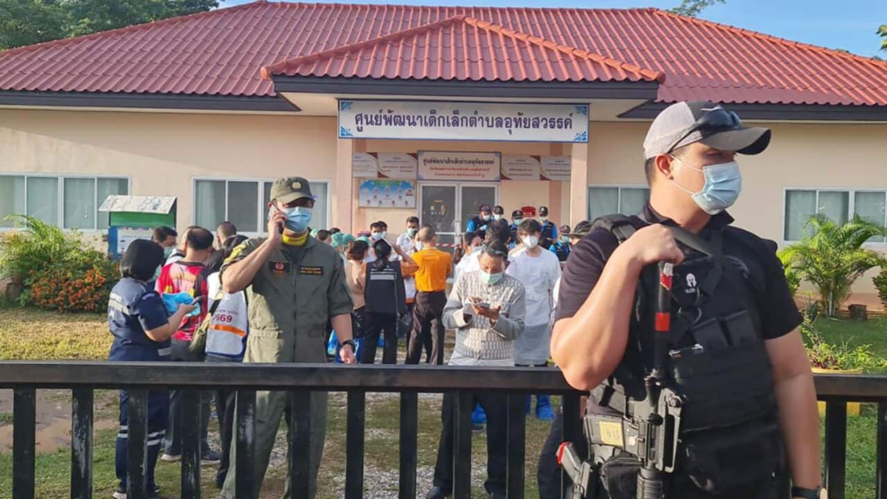 An armed police officer standing guard as relatives of the victims of a mass shooting gather at a childcare centre in Nong Bua Lamphu province, northeastern Thailand.
