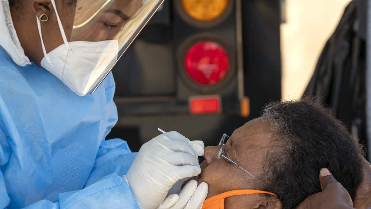 An woman reacts as a heatlh worker collects a sample for coronavirus testing outside of Johannesburg.