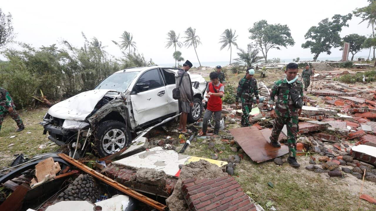 Rescuers walk among debris after a tsunami hit Sunda Strait, in Tanjung Lesung, Banten, Indonesia.