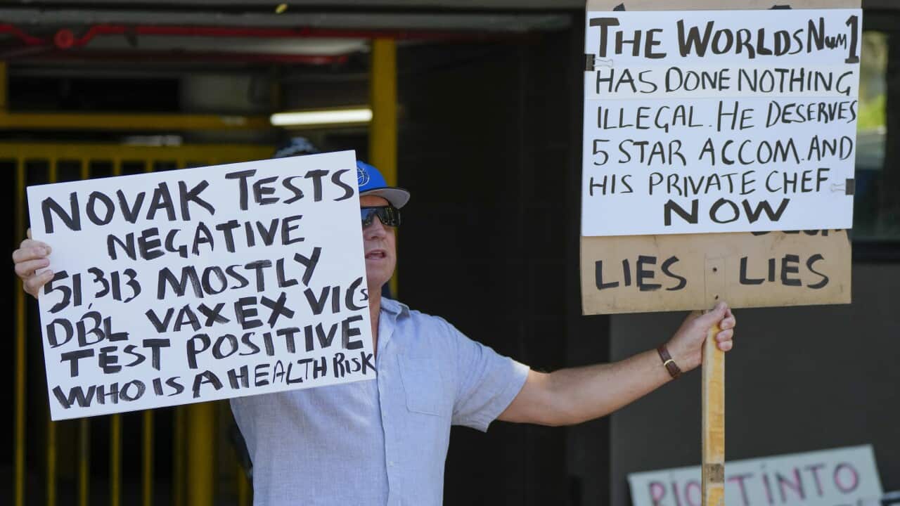 A supporter of Serbian Novak Djokovic holds placards outside an immigration detention hotel where Djokovic is confined in Melbourne, Australia, Monday, Jan. 10, 2022. After five nights in hotel detention Novak Djokovic will get his day in court on Monday