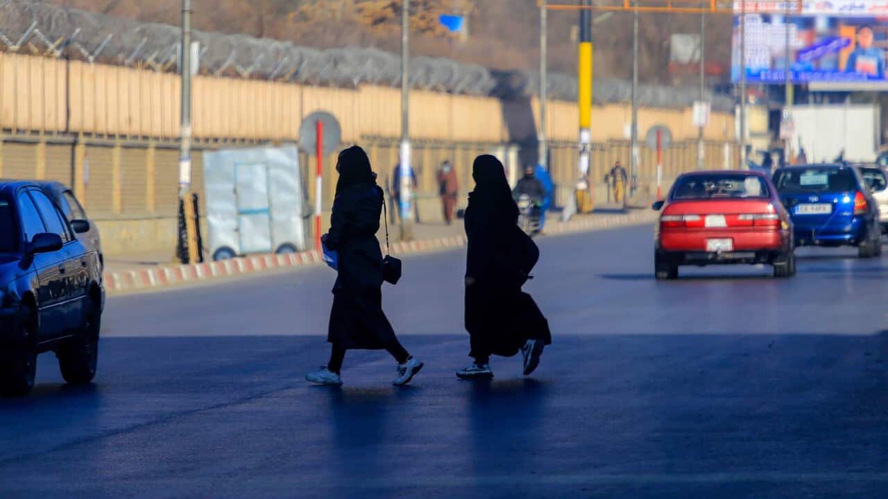 Side on view of two women walking in Afghanistan.