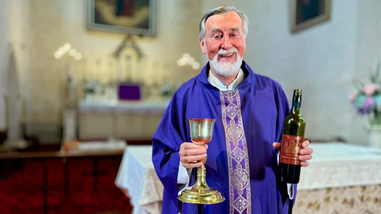 Father Brendan Kelly, Superior at Sevenhill Jesuit Mission in South Australia, holding sacramental wine which is still made on site, as it has been for 175 years. (SBS -Lloyd Thornton).jpg