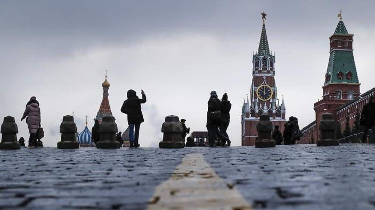 Tourists take pictures of the Kremlin, right, as they visit the Red Square in downtown Moscow, Russia on Friday, Dec. 30, 2016. (AP Photo/Alexander Zemlianichenko)