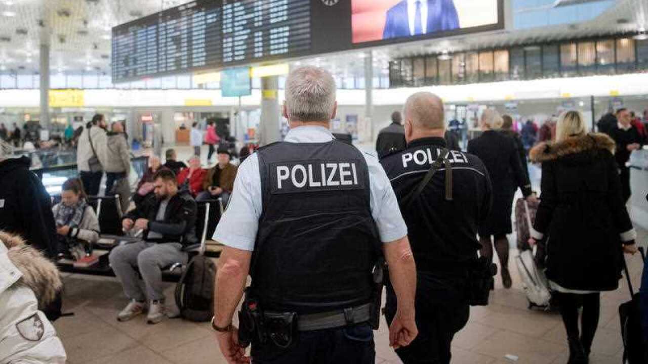 Police walk through Hanover Airport. Flights were suspended after a man drove his car onto the tarmac.