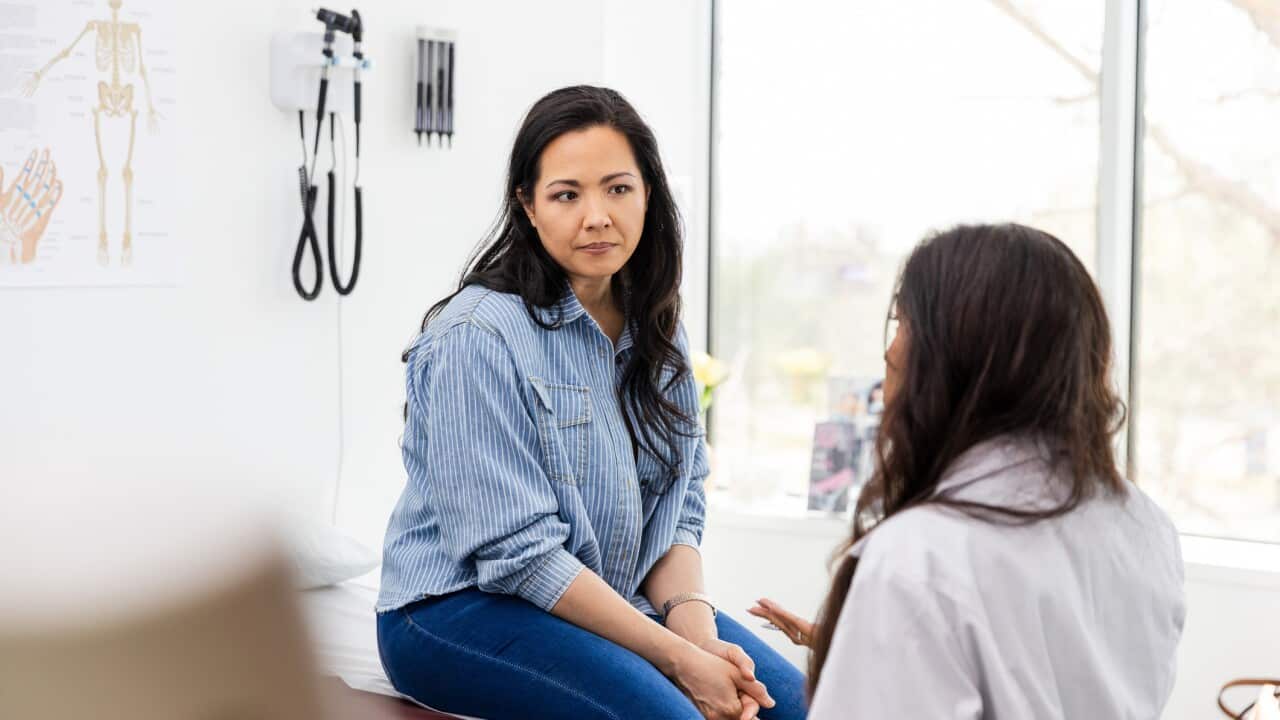 Woman speaks to a female doctor during a consult.