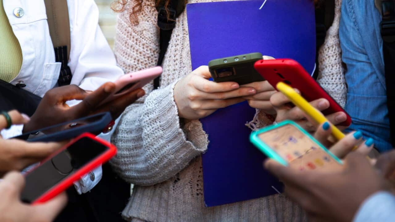 Close up of young college students hands holding mobile phones. Teenagers addicted to smartphones and technology. Group of friends sharing content on social media.