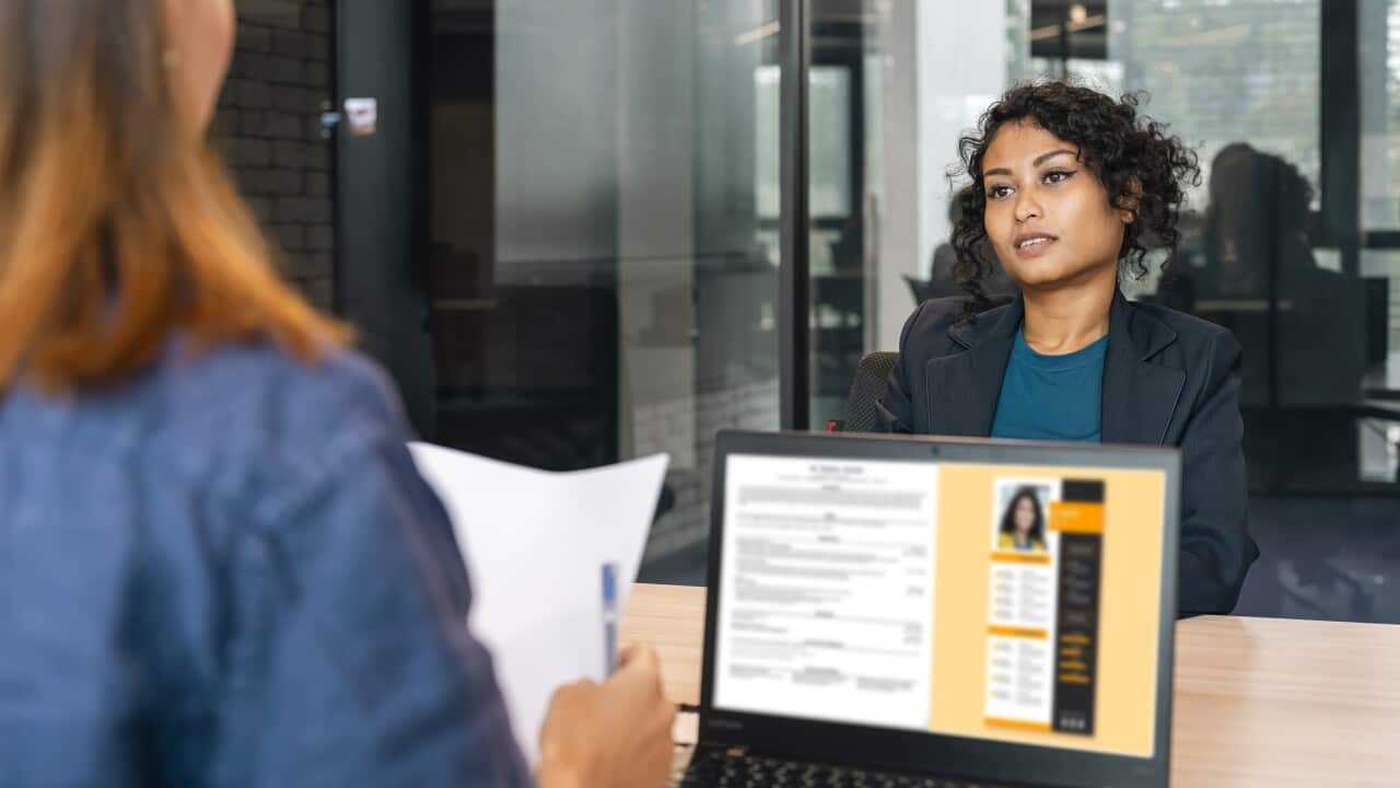Recruiter holding candidate resume taking job interview at desk.