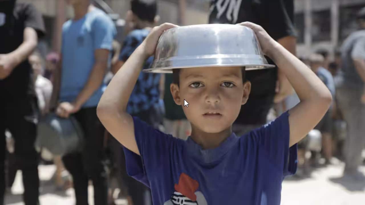 A boy holds a cooking pot on his head in Jabalia refugee camp.png