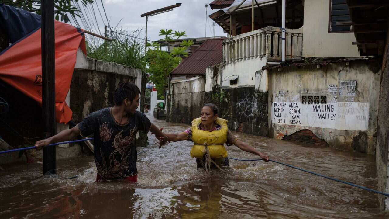 Citizens struggle to make their way through a flooded neighbourhood of Jakarta.