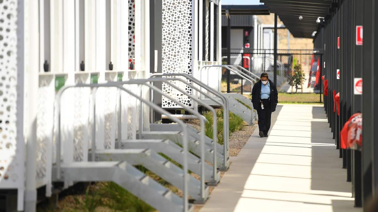 A person wearing a face mask employee walking along a path at the newly constructed Victorian quarantine accommodation hub in Mickleham, Melbourne.