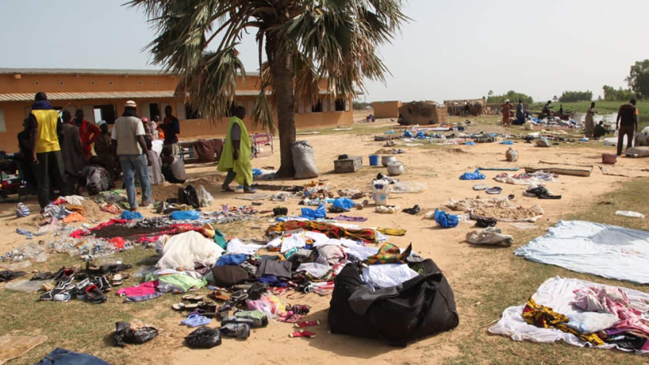 People who survived a sinking of a river boat stand near belongings