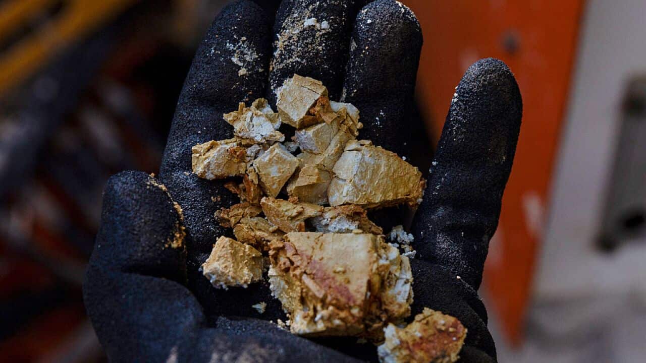A gloved hand holds a rare earth minerals deposit