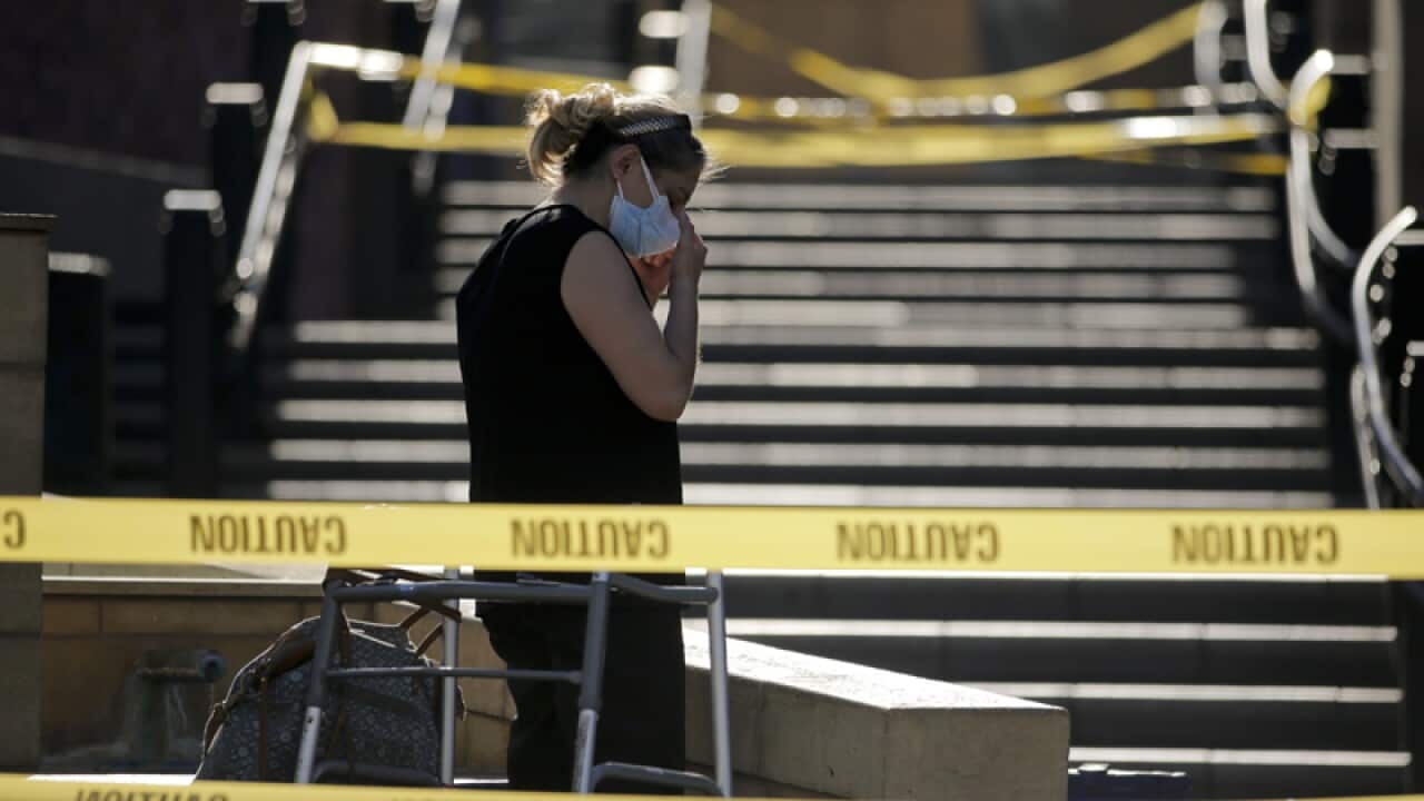 A woman adjusts her mask outside the closed-off Patsaouras Plaza