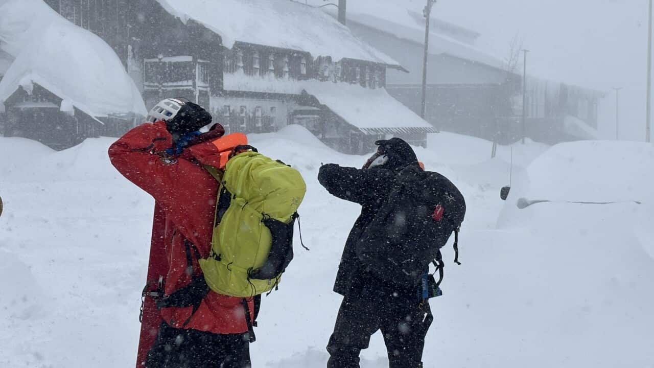 Two people walking in heavy snow.