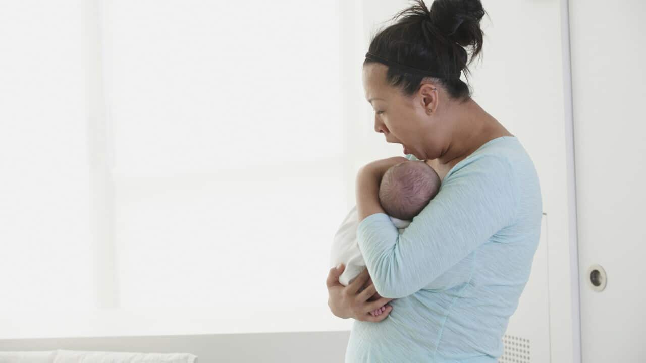 Yawning mother holding newborn