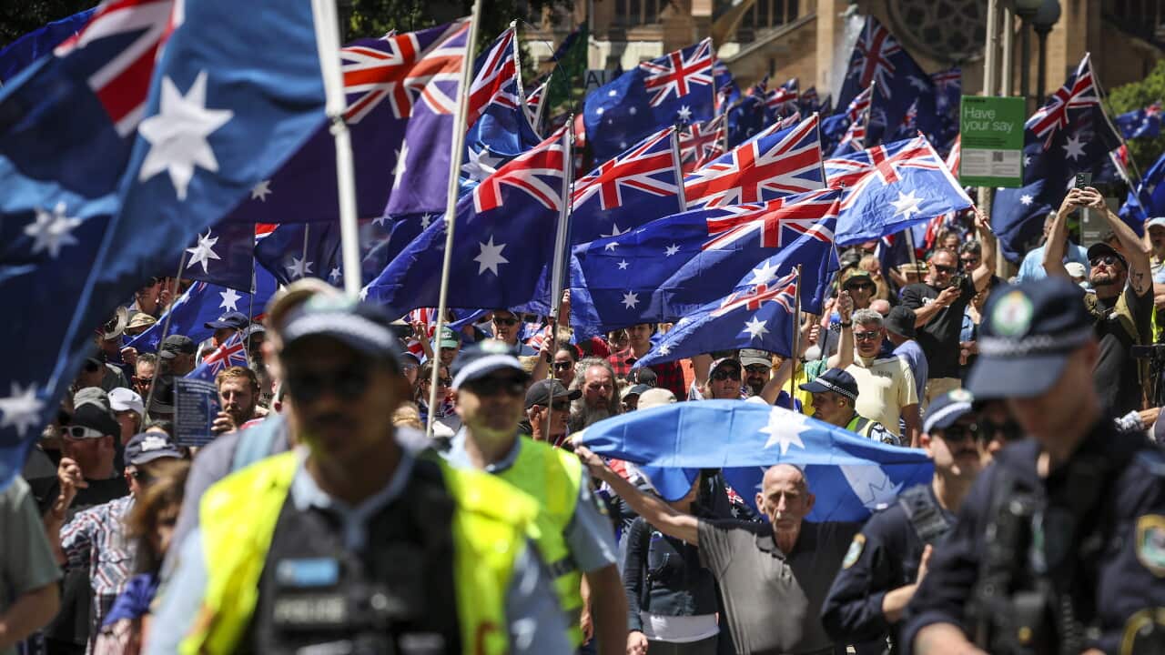 Agenti della polizia del New South Wales accanto ai manifestanti con bandiere nazionali australiane e striscioni durante la “March for Australia” del 19 ottobre 2025.