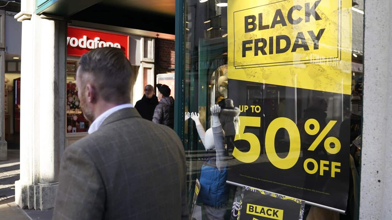 A man in a suit walking past a black and gold sign that reads: 'Black Friday, up to 50 per cent off"