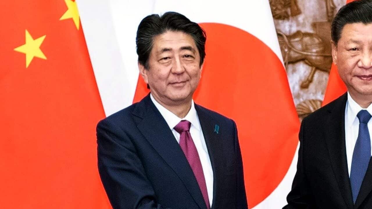 Japanese PM Shinzo Abe, left, shakes hands with Chinese President Xi Jinping during a rare visit.
