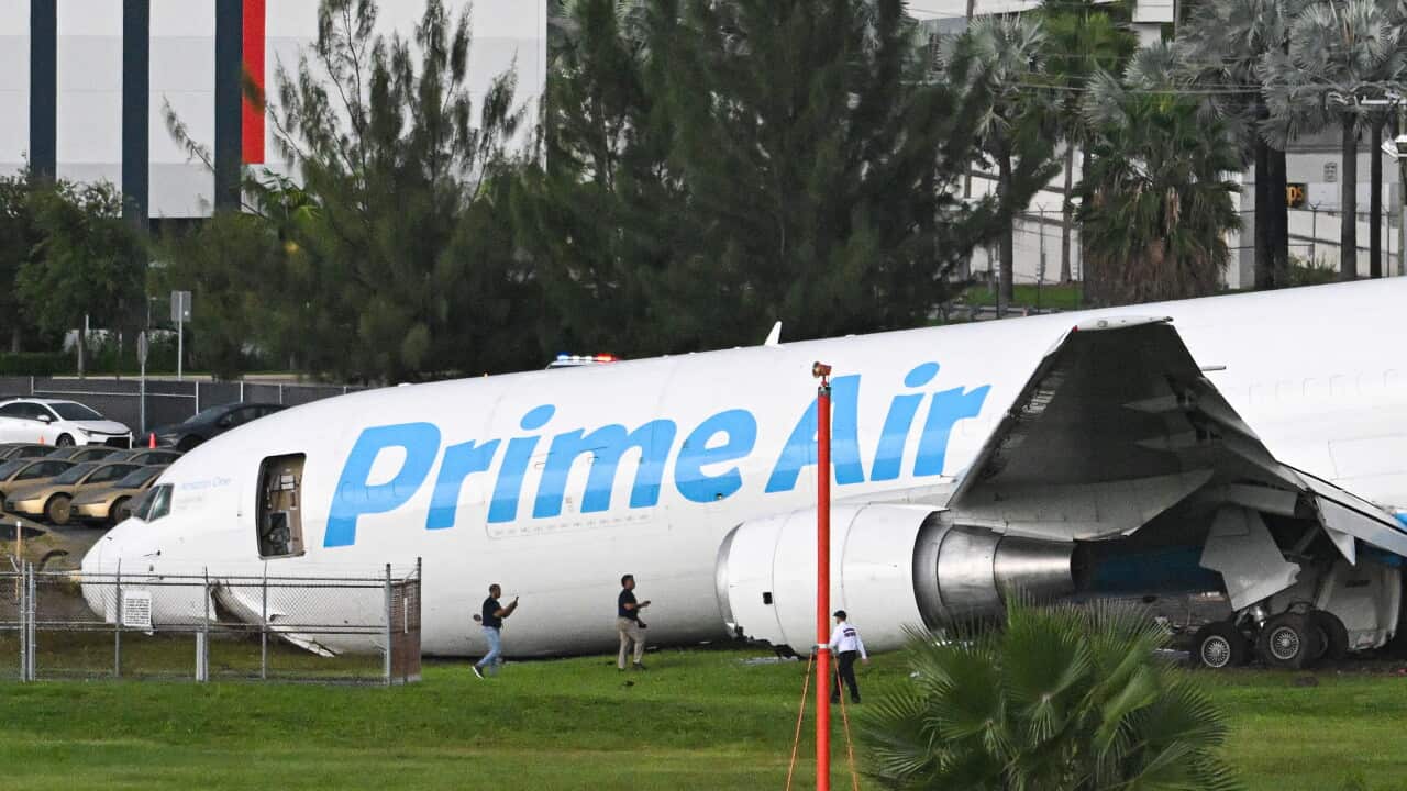 Crashed prime air plane next to vehicles and grass