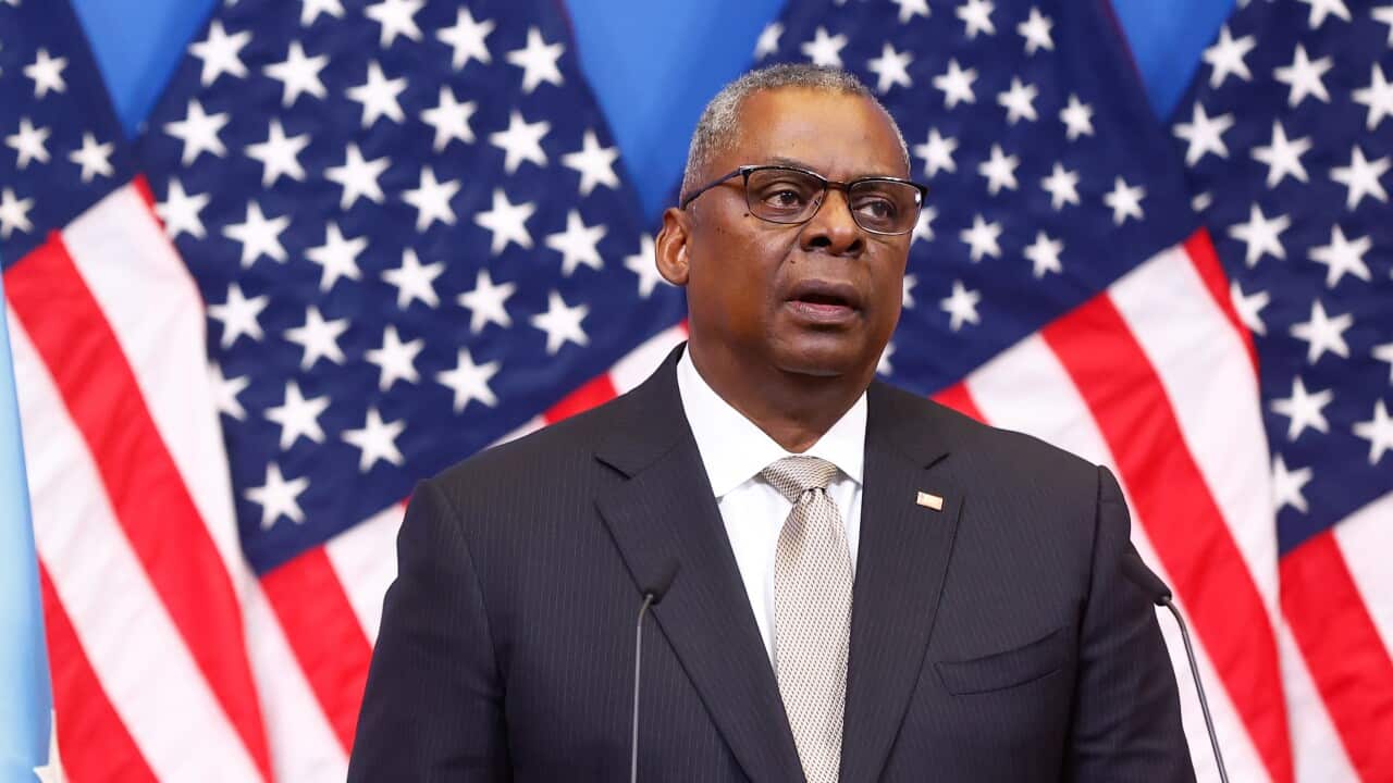 US Defence Secretary Lloyd Austin standing in a suit in front of the US flag.