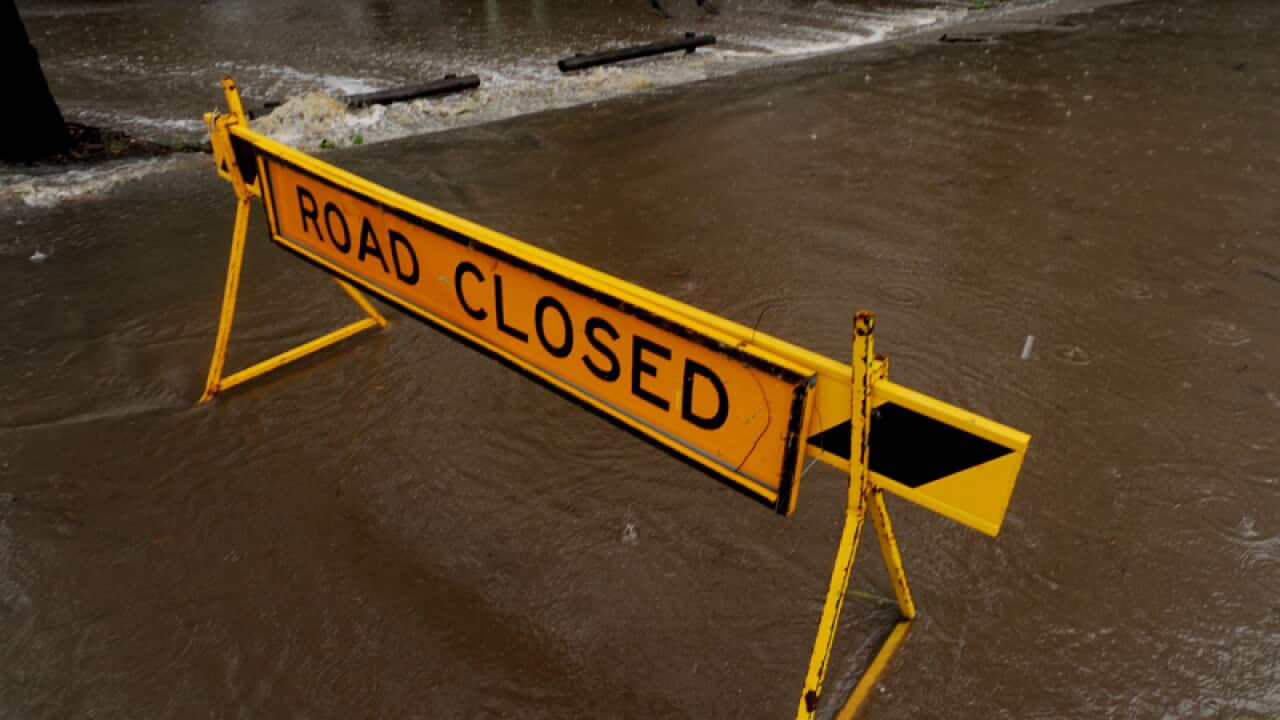 A road closed sign blocks a crossing at flooded causeway