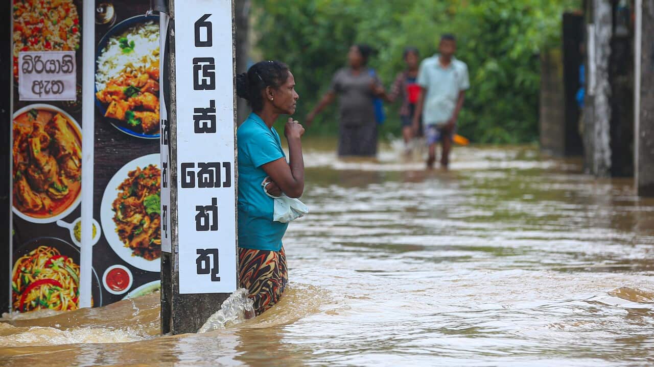 A woman stands in thigh-deep floodwaters