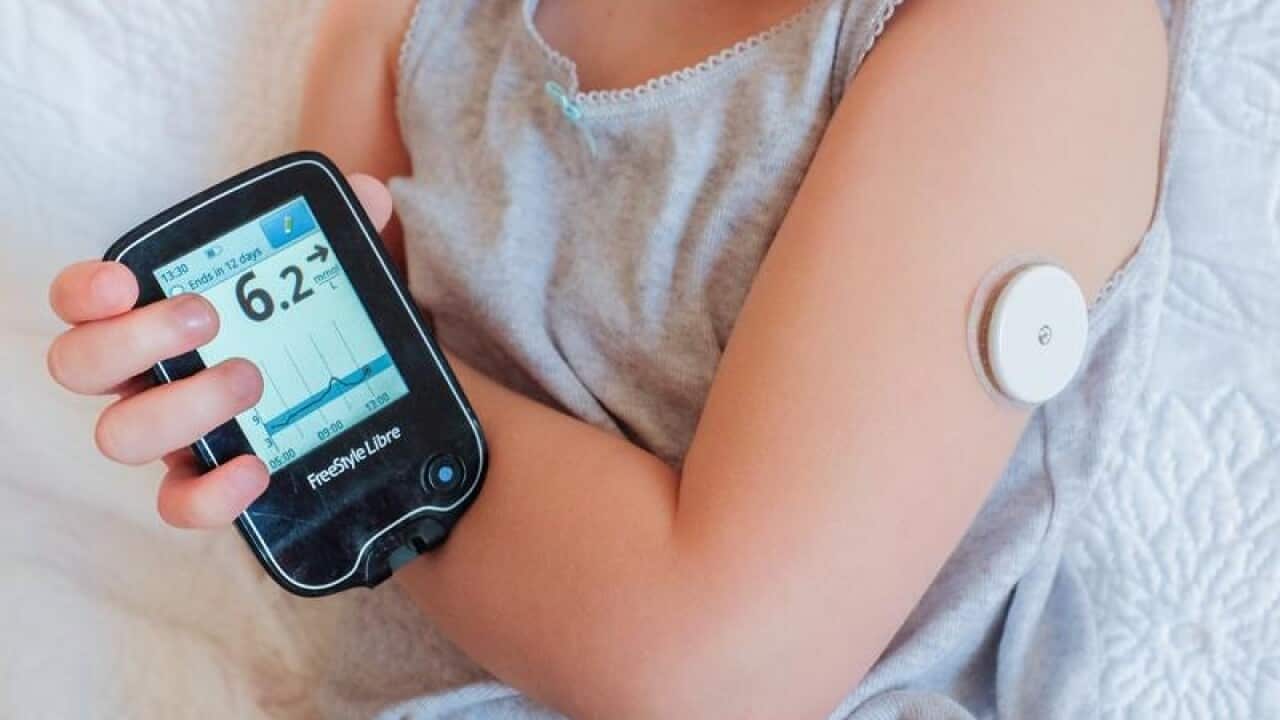 A child checks her blood sugar by using a sensor device.
