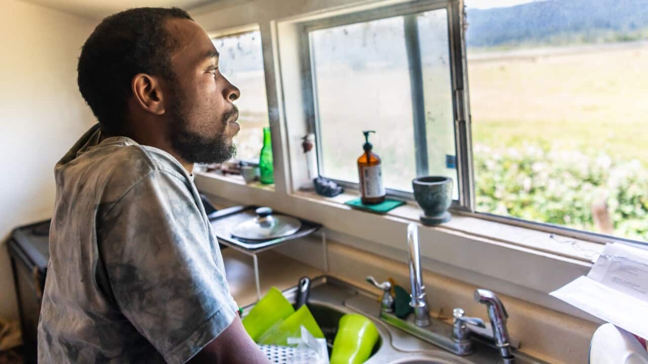 Serious black mid adult man looking through a window