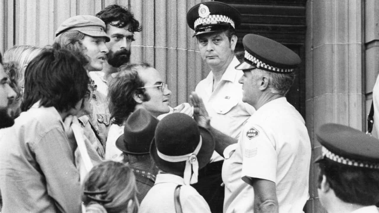 A black and white image of police confronting a group of protesters.