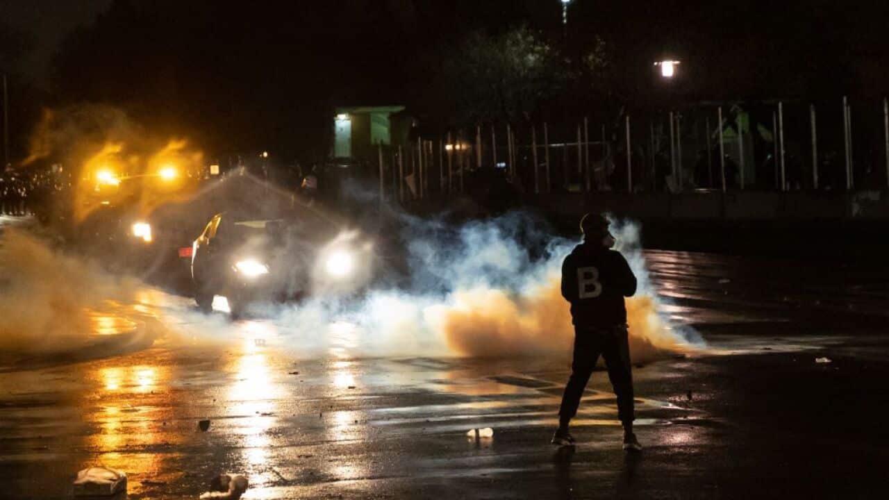 Protesters try to shield themselves from tear gas fired by police outside the Brooklyn Center police station, April 12, 2021
