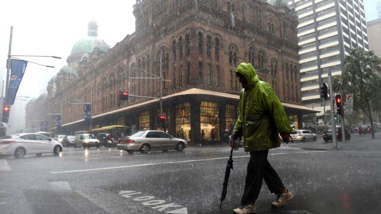 A pedestrian crosses the street during heavy rain in Sydney on Monday.